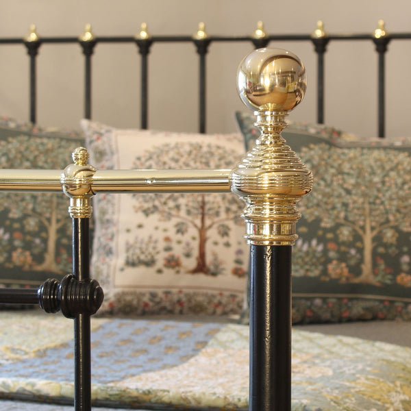 Close-up of a decorative bedpost with gold and black finish, featuring intricate design.