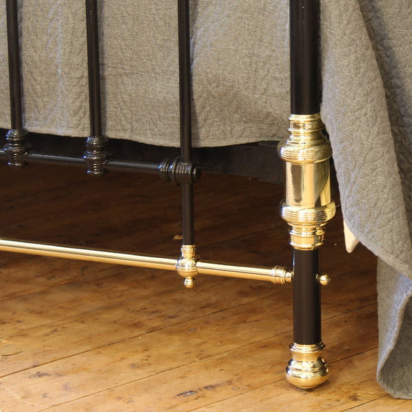 Close-up of a bed with brass and black metal legs on a wooden floor.