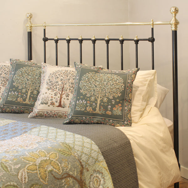 Decorative pillows with floral patterns on a bed with a black and gold headboard.