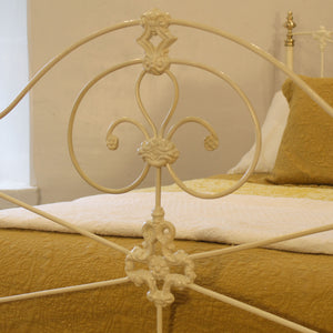 Close-up of a decorative metal bed frame with yellow bedding.