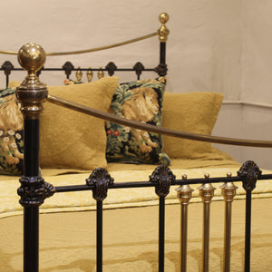 Close-up of a decorative iron bed with gold accents and patterned pillows.