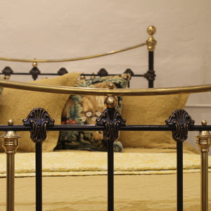 Decorative metal bed frame with gold accents and pillows on a beige background