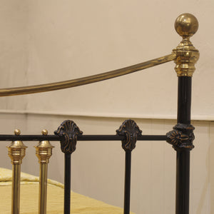 Close-up of a decorative metal antique bed frame with gold and black details.