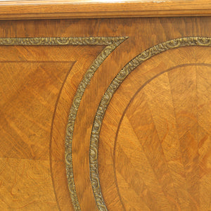 Close-up of an ornate wooden headboard featuring intricate inlay patterns in warm honey and medium brown tones, with a decorative metallic gold border.