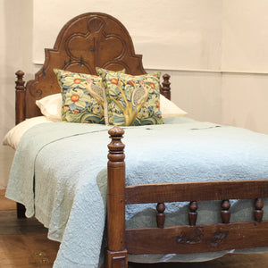 Bed with wooden headboard and decorative pillows on a light background
