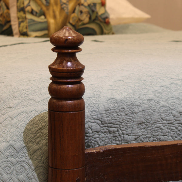 Wooden bed post with intricate design on a bed with textured bedding