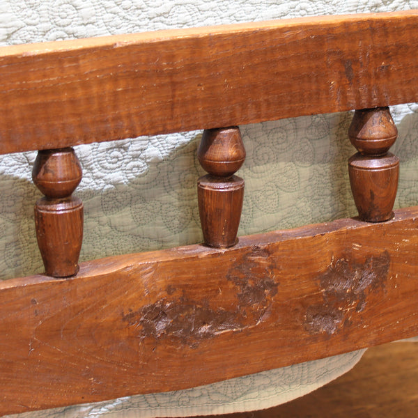 Close-up of an old wooden bench with worn surface and decorative legs.