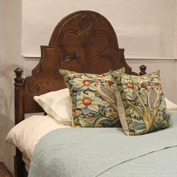 Decorative pillows with floral patterns on a bed with a wooden headboard.