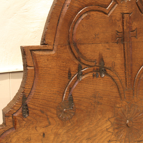 Close-up of a wooden panel with intricate carvings and a visible brand logo.